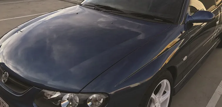A dark car bonnet polished to a mirror finish at the VMClean workshop