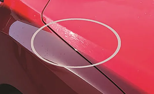 Red paintwork showing a dense web of fine swirl marks under direct light